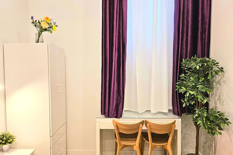 Escritorio con dos sillas bajo la ventana de cortinas moradas