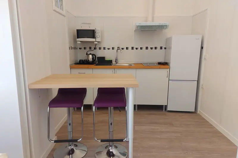 Cocina del estudio con barra, taburetes morados, nevera y microondas
