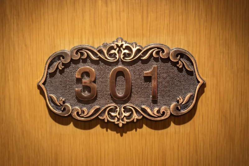 Placa de bronce con el número 301 en una puerta de madera